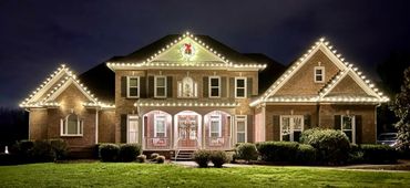 Large brick house decorated with Christmas lights at night.
