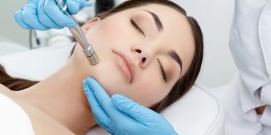 Woman receiving a facial treatment with a medical device.