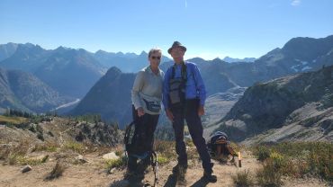 Couple hiking in mountainous terrain on a sunny day.