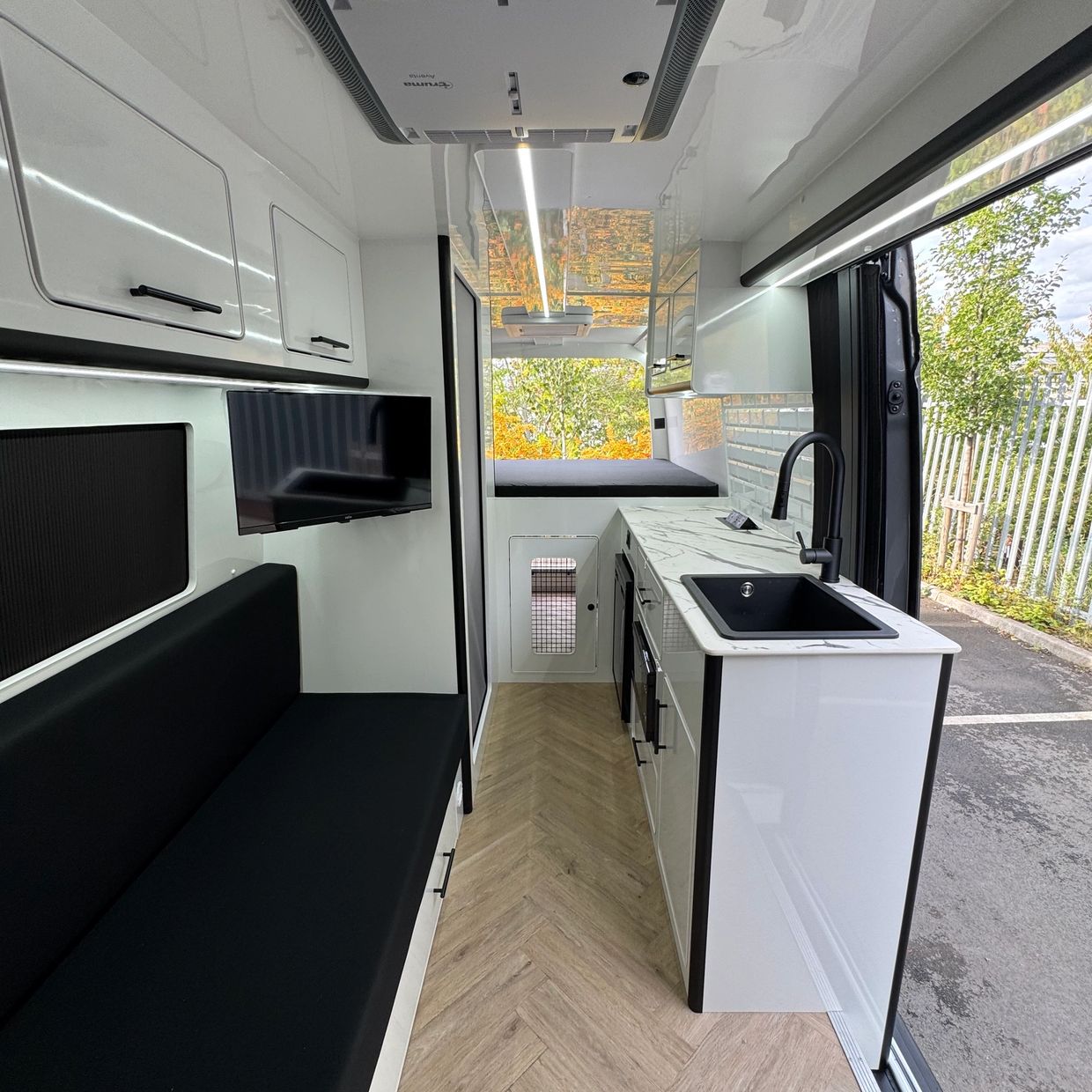 Modern camper van interior with sleek kitchen and seating area.