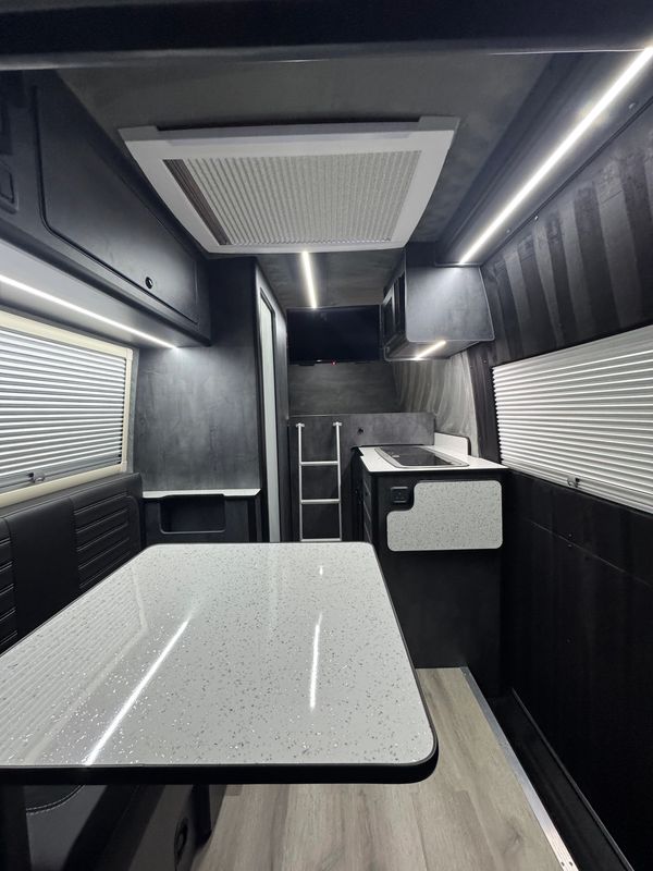 Interior of a modern camper van with dining and kitchen area.