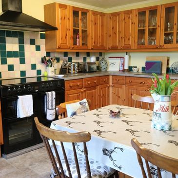 Cozy kitchen with wooden cabinets and a tablecloth-covered dining table.