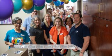 Group cutting a ribbon at an event.