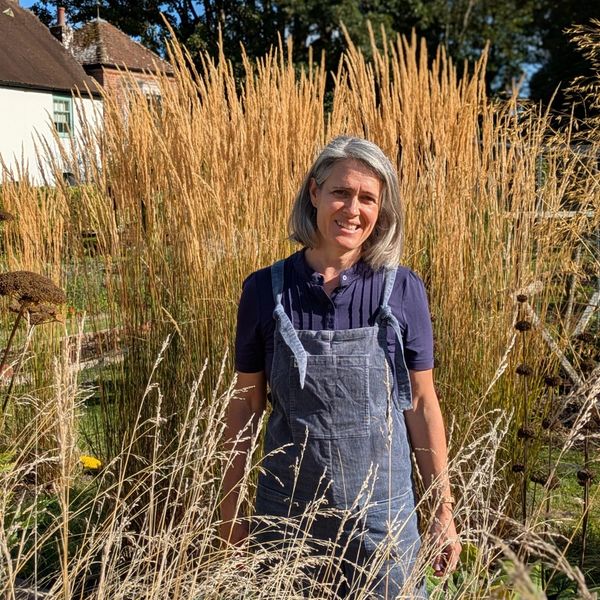 Woman standing in tall grass with a smile on a sunny day.