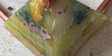 Decorative resin piece with seashells and small objects.