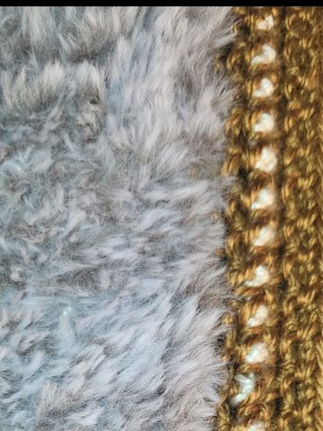 Close-up of gray fur beside brown knitted fabric.