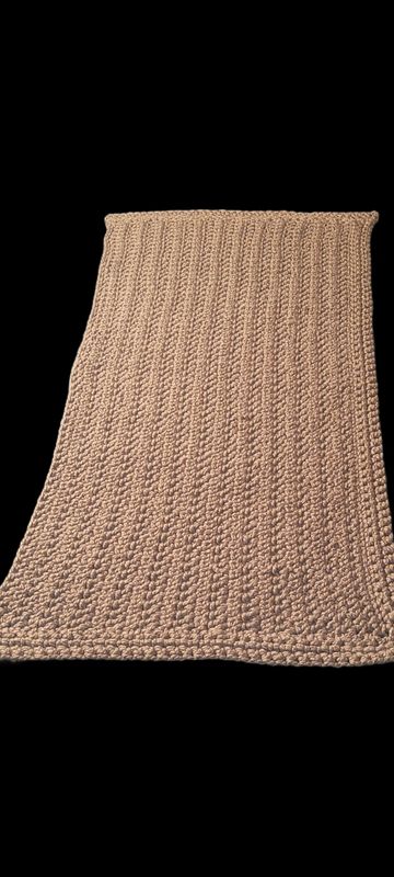 Handmade beige crocheted blanket with textured pattern.