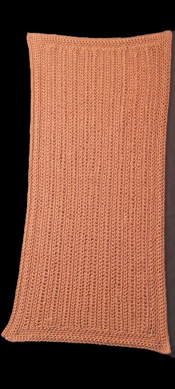 A peach-colored rectangular knitted cloth with a textured pattern.
