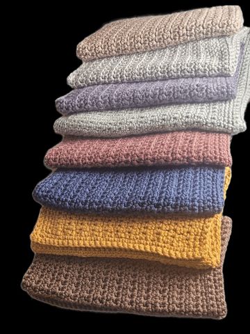 Stack of colorful knitted blankets with various textures.