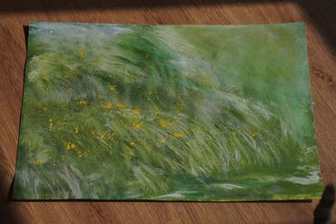 Abstract green painting with textured yellow highlights on a wooden floor.