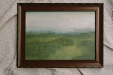 Framed painting of a misty green landscape with soft blending.