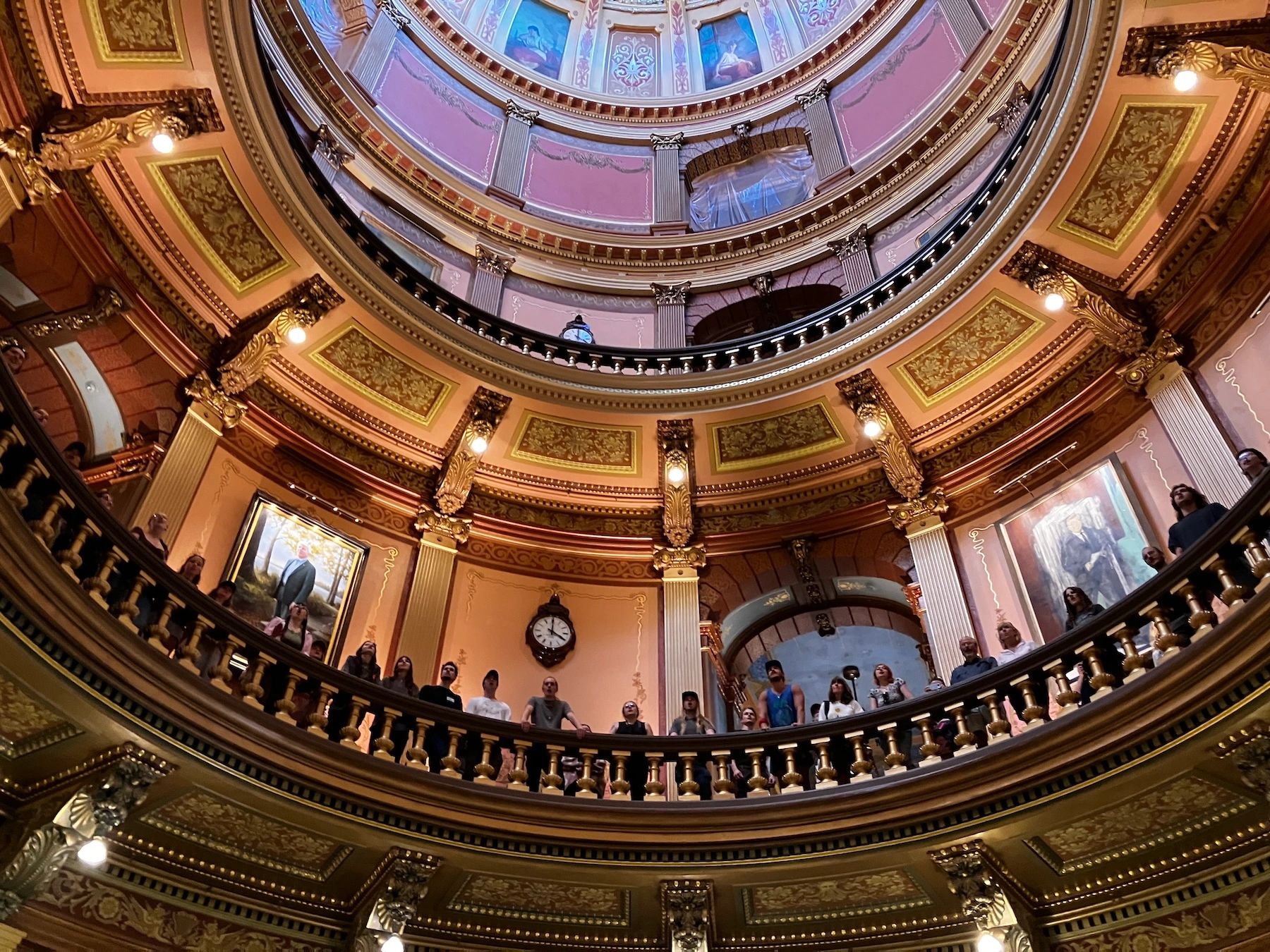 Ornate round balcony with people looking up inside a historic building.