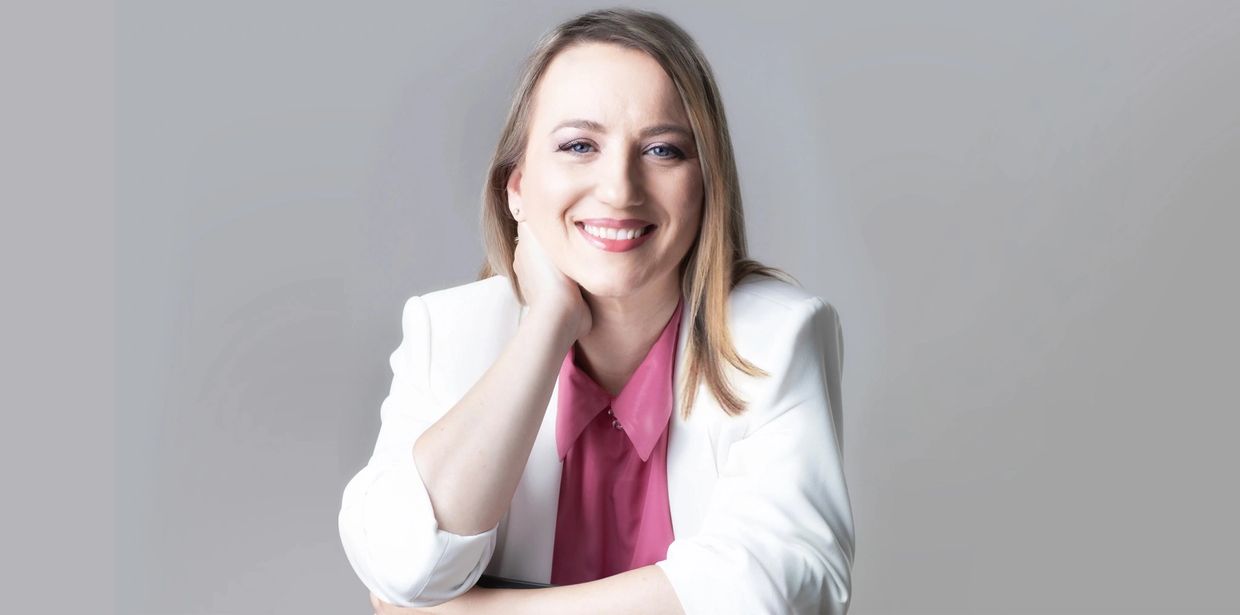 portrait of a woman wearing a pink blouse and white jacket