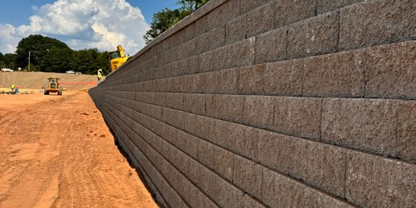 Long retaining wall under construction with construction equipment in the background.