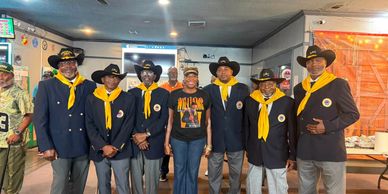 Group of men in matching cowboy hats and scarves with a woman in the middle.