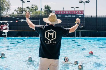 Coach instructing water polo players in pool.
