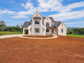 Modern countryside house with a large yard under a blue sky.