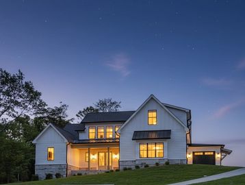 Modern white house illuminated at dusk.