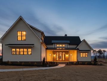 Modern white house exterior at dusk with warm lights.