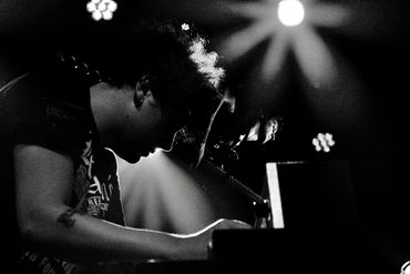 Black and white photo of a musician playing piano on stage.