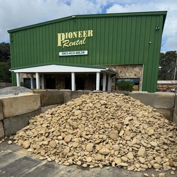 Pile of smooth stones in front of a green rental building.