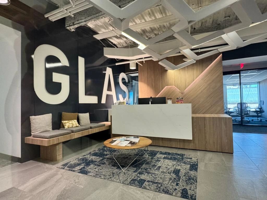 Modern office reception with wooden decor and large wall letters.