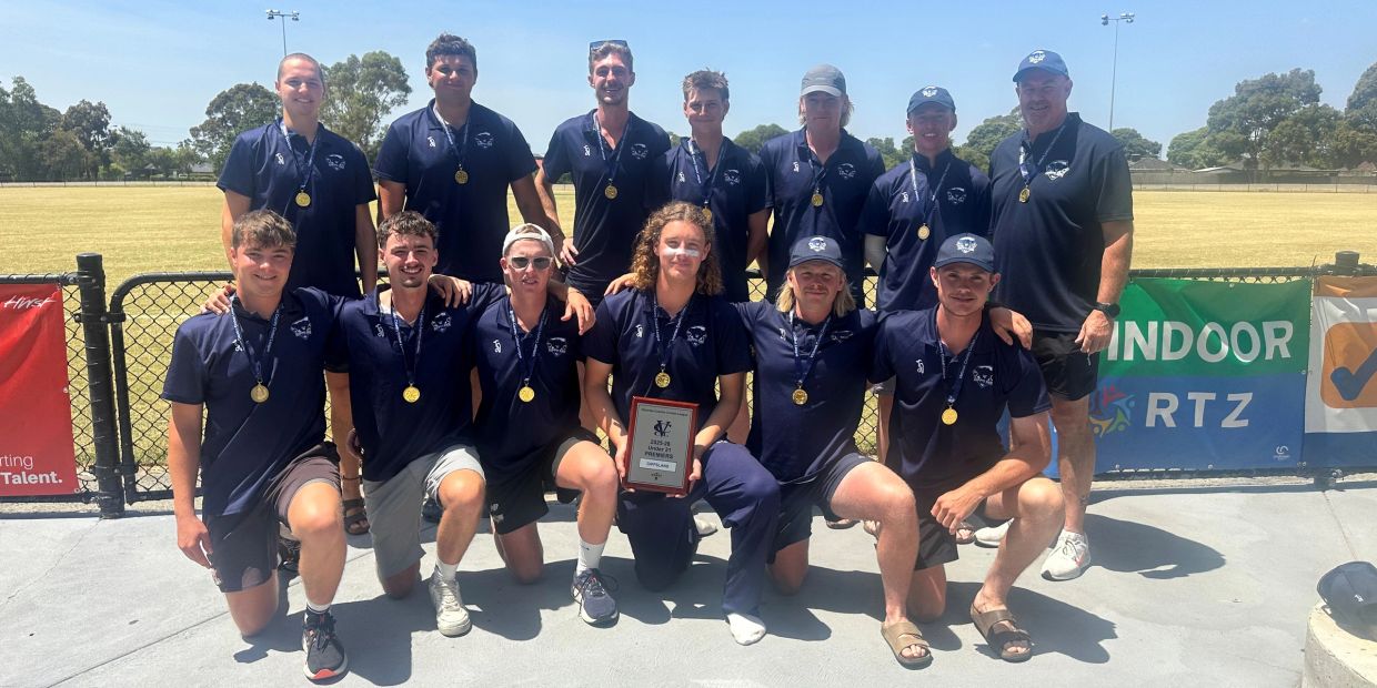 A sports team posing with medals and a plaque outdoors on a sunny day.
