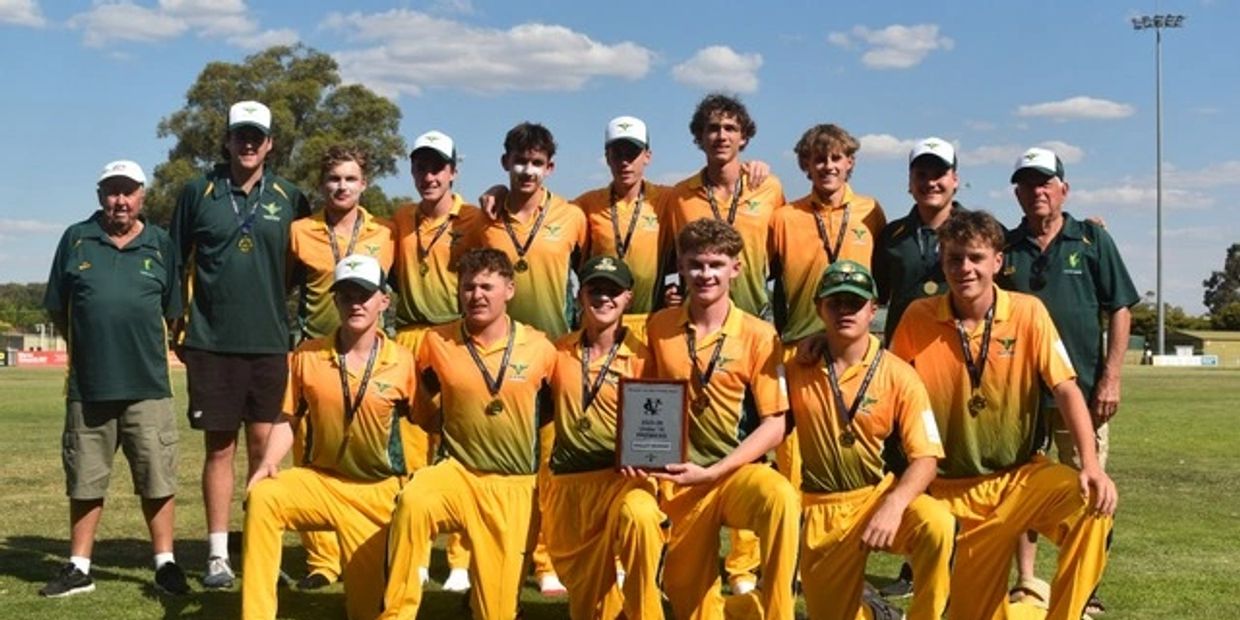 Youth cricket team posing with medals and a trophy on a sunny day.