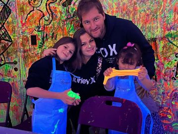 A family enjoys a colorful glow-in-the-dark art activity together.