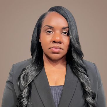 Professional woman with long black hair in a black blazer against a neutral background.