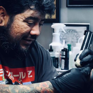 Tattoo artist focused on inking a client's skin with a tattoo machine.