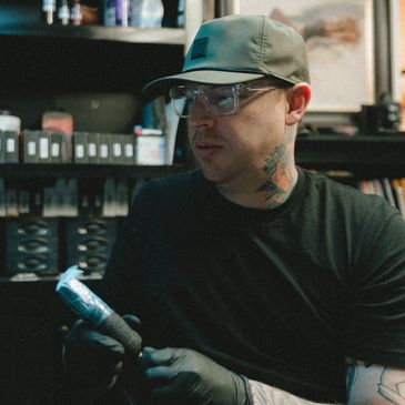 Tattoo artist holding a tattoo machine in a studio.