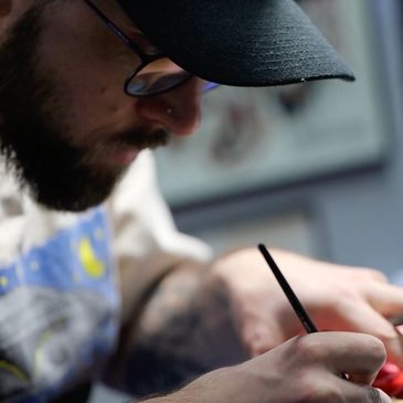 Man wearing a cap and glasses painting with focus.