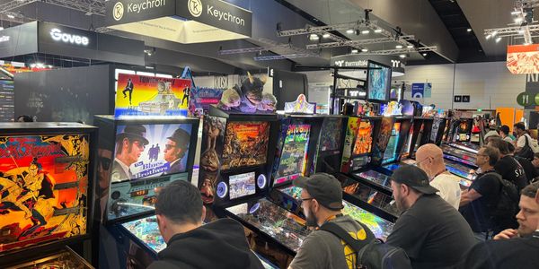 People playing pinball machines at a gaming event.
