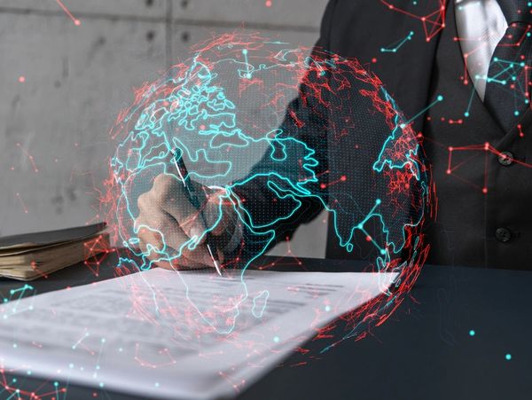 Businessman in suit signs contract. Double exposure with world map hologram.