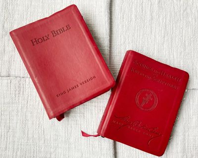 Two red books laying on a white table cloth.