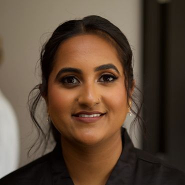 Close-up portrait of a smiling woman with dark hair and makeup.