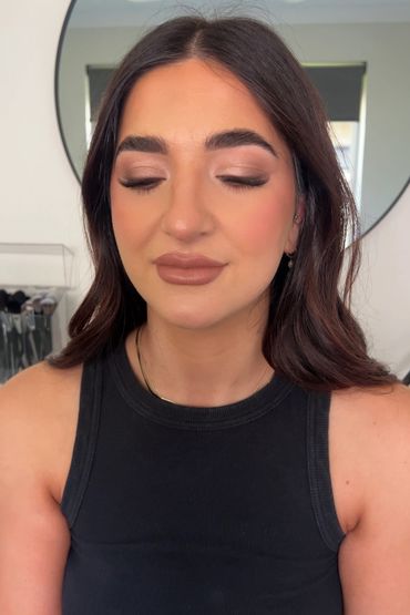 Woman with flawless brown-toned makeup and closed eyes.