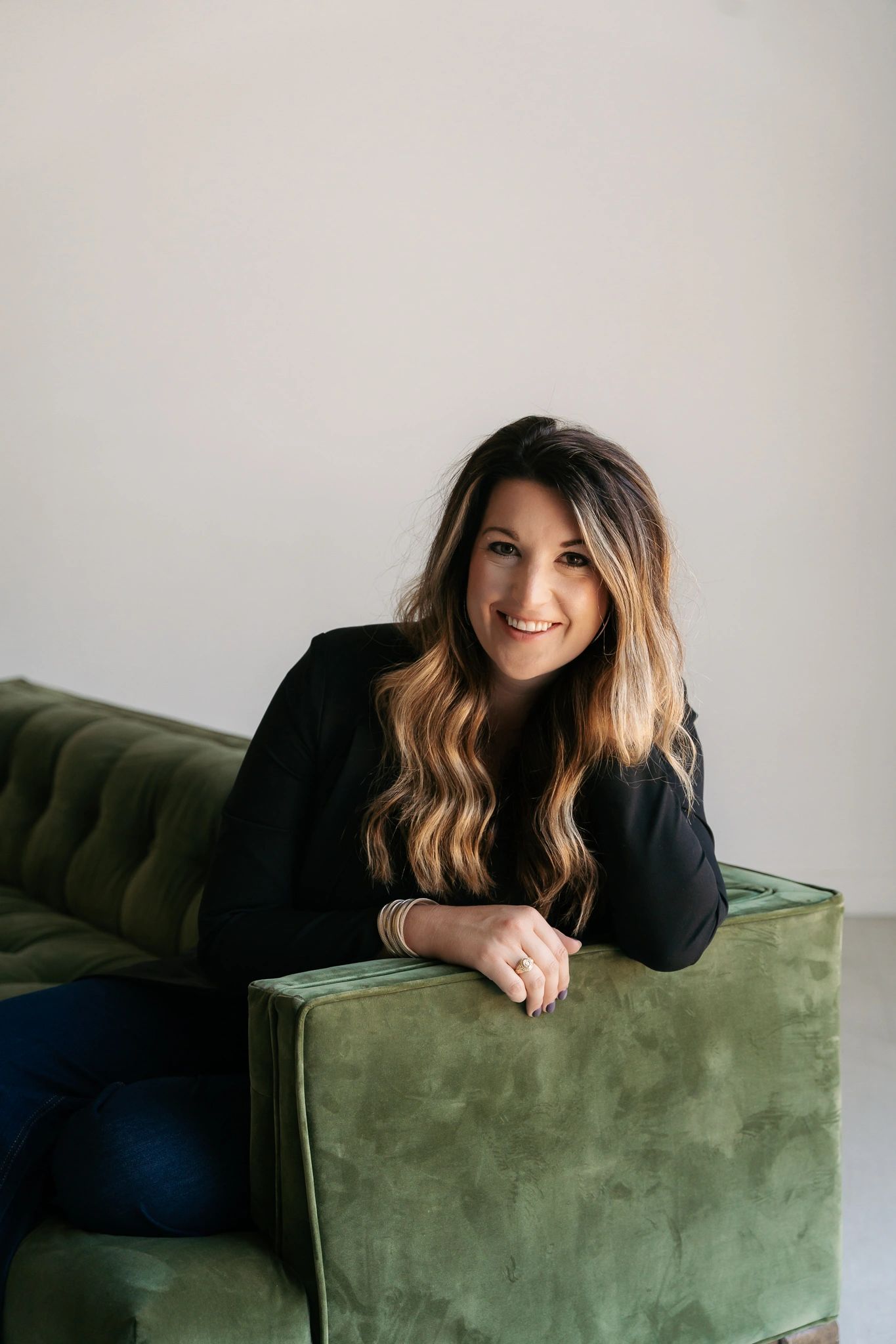 Annie Waneck, a Bastrop, Texas mortgage loan officer, smiling while seated on a green velvet couch.