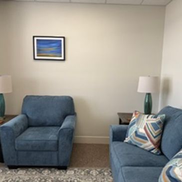 Cozy living room corner with blue armchair and sofa.
