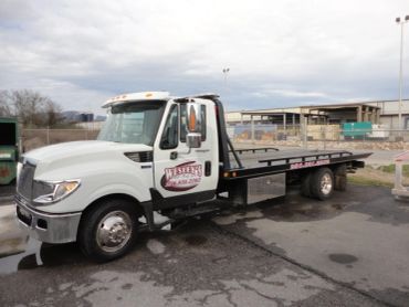 White flatbed tow truck parked outdoors.