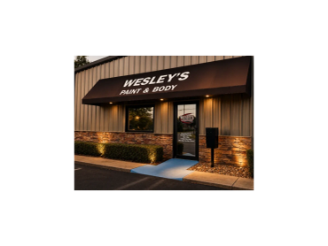 Exterior of Wesley's Paint &amp; Body shop with lit sign.