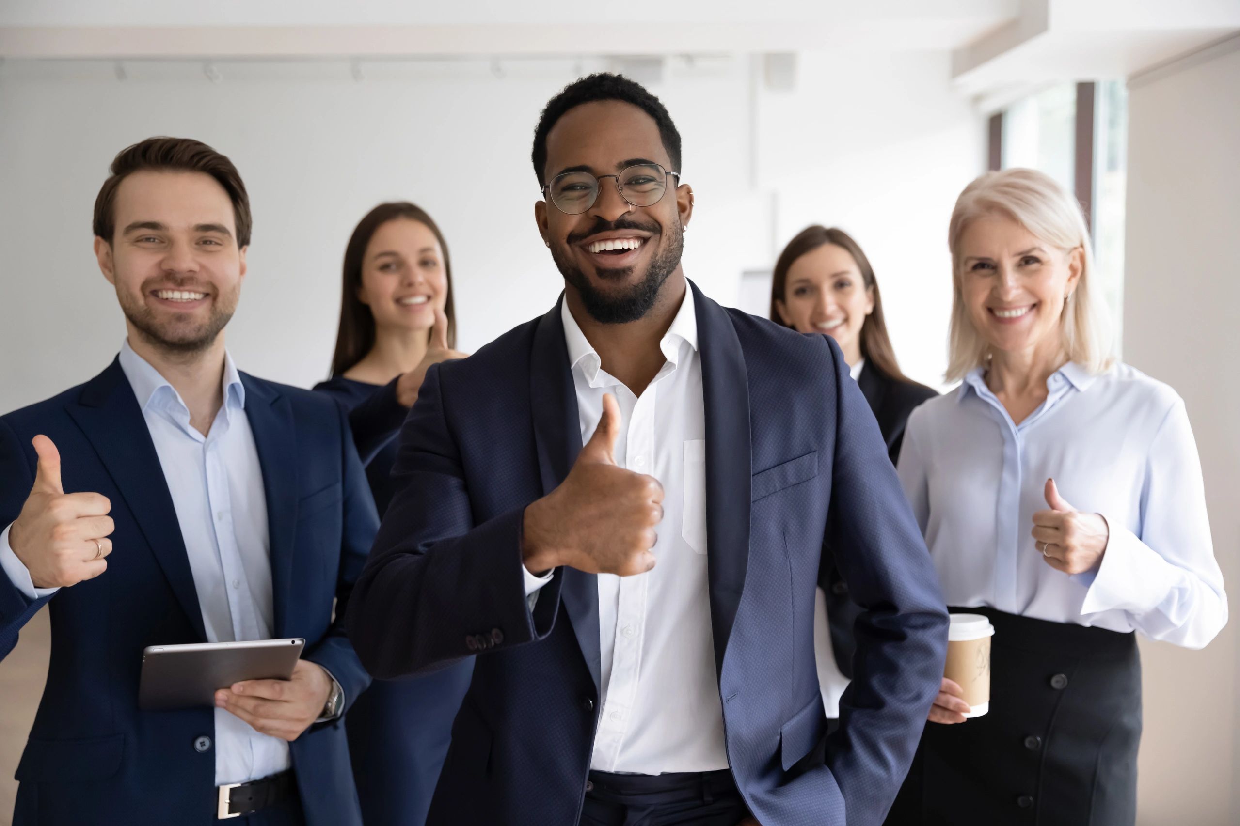 Business professionals giving the thumbs up and smiling joyfully.