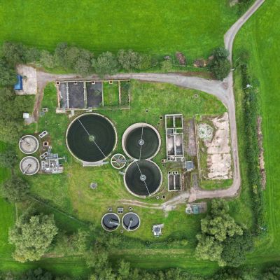 Aerial view of a wastewater treatment plant surrounded by green fields and trees.