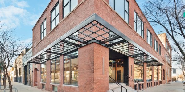 Modern brick corner building with large windows and glass canopy.