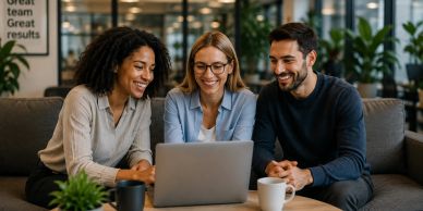 Three colleagues smiling and looking at a laptop in a modern office.