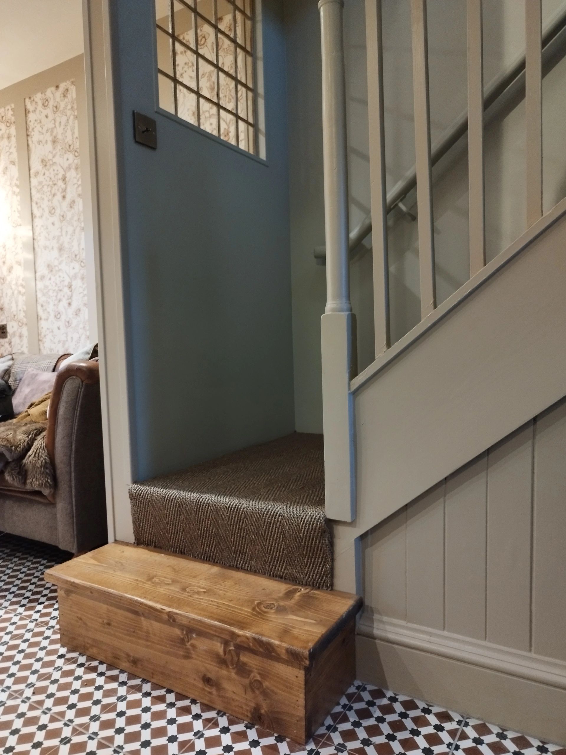 Wooden chest in a cozy hallway with stairs.