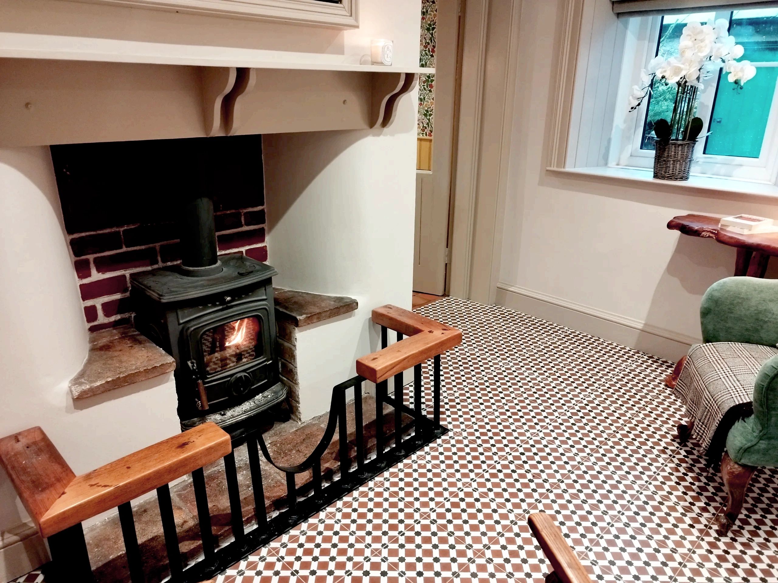 Cozy room with a lit wood stove and checkered tile floor.