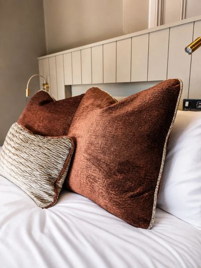 Brown and patterned pillows on a white bed.