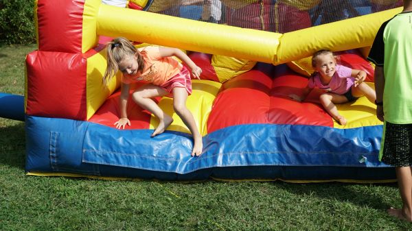 Two children playing on a colorful inflatable bounce house outdoors.